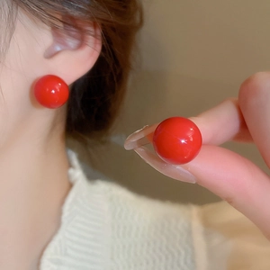 Detailed close-up of glossy red spherical stud earrings with minimalist resin finish