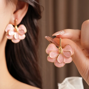 Detailed view of vintage pink flower earrings with golden edges on model's hand