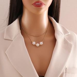 Close-up of golden multi-layer necklace with pearl charms on a professional model