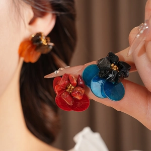 Close-up of vintage flower earrings with colorful shell petals and gold bead center