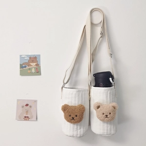 Quilted cotton cup sleeve featuring embroidered bear motif and adjustable shoulder strap