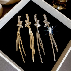 Detailed view of long gold and silver tassel earrings with zircon stones on black velvet