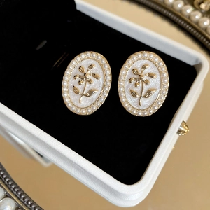 Macro view of gold plated floral earrings with pearls and mother-of-pearl inlay