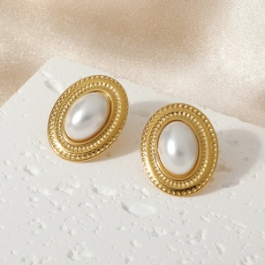 Macro detail of vintage gold pearl earrings with beaded edge on silk background