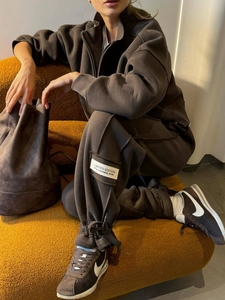 Deep brown two-piece tracksuit featuring a half-zip top and drawstring joggers on a sofa