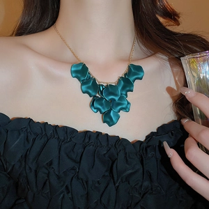Close-up of a layered dark green petal fringe necklace on a gold metal chain