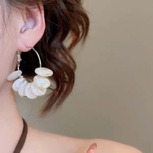 Detailed close-up of resin hoop earring with white mother-of-pearl beads and silver studs