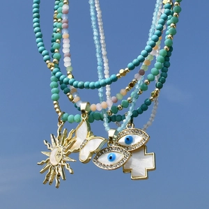 Collane di perline boho con ciondoli farfalla, malocchio e stella solare su sfondo cielo blu