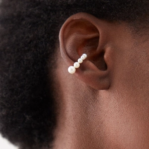 Detail of five gradient white pearls on silver ear cuff earring worn by a model