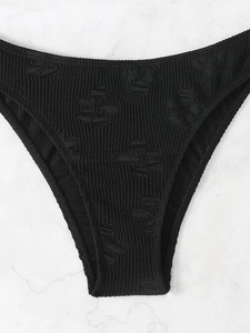 Detail of black smocked bikini bottoms featuring textured fabric and 3D bow patterns