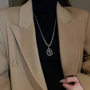 Détail du collier argenté avec pendentif goutte foncée sur col roulé noir