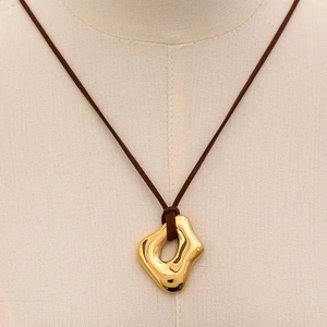 Detail of liquid gold geometric pendant with brown cord on mannequin neck