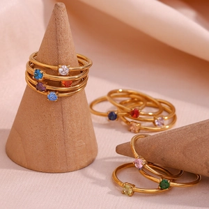 Close-up of thin gold rings with round birthstones on a wooden cone display stand