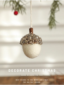 Close-up of acorn felt Christmas tree ornaments with sequins hanging on a pine branch