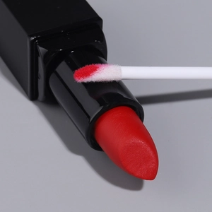 Macro view of red solid lipstick texture and white applicator brush for precise lip application