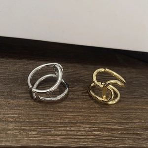 Close-up of overlapping twisted geometry rings in gold and silver metallic finishes
