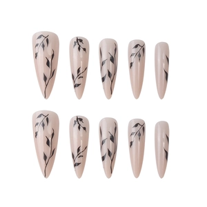Long stiletto press-on nails featuring nude pink base and black hand-painted leaf patterns