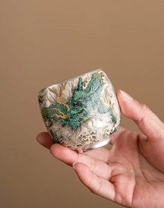Detailed close-up of a ceramic tea cup with exquisite green dragon and cloud patterns