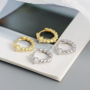 Close-up of twisted rope hoop earrings with square diamonds in gold and silver finish