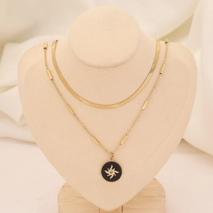 Gros plan du collier double doré avec chaîne serpent plate et pendentif soleil sur buste