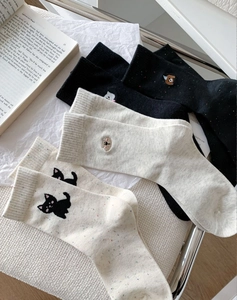 Close-up of knit crew socks with embroidered dog patterns on a soft background