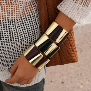 Detail of chunky gold and dark acrylic geometric link bracelet on woman's wrist