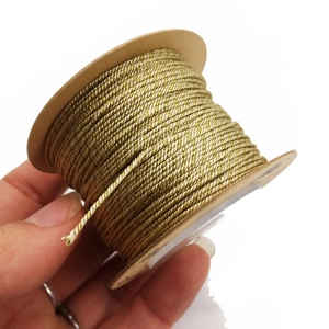 Close-up of hand-held 1mm metallic gold thread spool for DIY jewelry and crafts