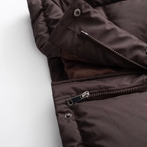 Macro shot of dark brown quilted jacket with metallic zipper and glossy waterproof fabric
