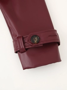 Détail du poignet d'une veste en similicuir bordeaux avec bouton écaille et boucle
