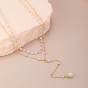 Elegant gold double layer necklace with pearls and Y-shaped tassel on natural stone background