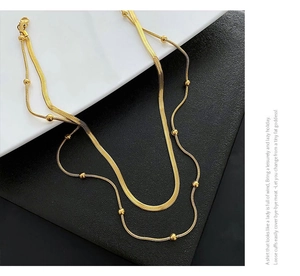 Detailed view of layered gold flat snake chain necklace with small metal beads