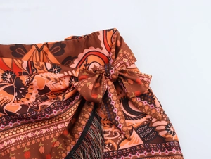 Detail of bohemian mini skirt with paisley print knot tie design and black fringe trim