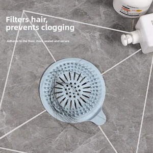 Dettaglio del copri scarico in silicone blu che filtra i capelli su pavimento marmoreo