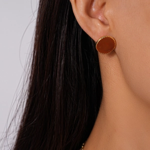 Gros plan de boucles d'oreilles dorées géométriques avec incrustation brun rouge