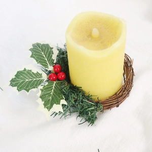 Détail d'une bougie LED de Noël avec verdure artificielle et baies rouges sur base