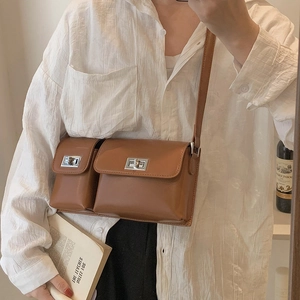Brown leather baguette bag with dual silver clasps styled with a white shirt and books