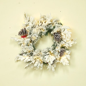 Christmas wreath with flocked needles, pine cones, red berries and warm LED lights