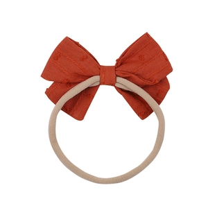Soft nylon baby headband with a textured bow in warm caramel orange color
