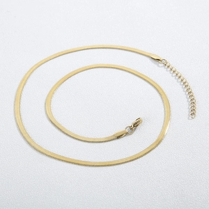 Flat gold snake chain necklace with lobster clasp and extender on textured white background