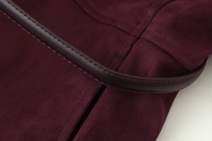 Detailed macro view of burgundy suede texture and premium stitching on a women jacket