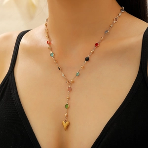 Gold chain necklace with colorful gemstones and a heart pendant shown on model