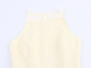 Détail de la robe en tweed crème avec fines bretelles et texture tissée élégante