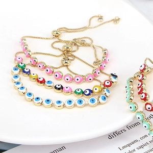 Bohemian evil eye bracelets with colorful beads and adjustable gold chains on a white plate