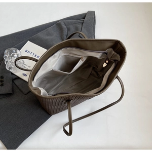 Detail view of brown woven tote bag interior with zipper and light gray fabric lining