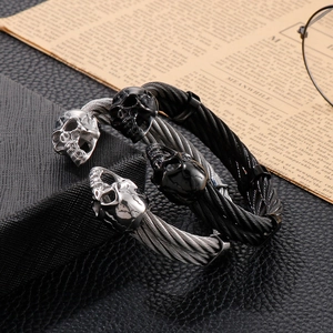 Detailed view of punk double skull heads on a twisted steel wire cable bracelet for men