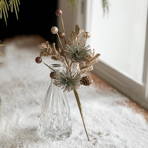 Décoration de branches avec pommes de pin dorées et baies dans un vase pour Noël