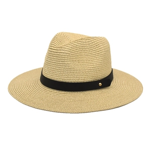 Detailed close-up of woven paper straw texture and black ribbon band on a fedora hat