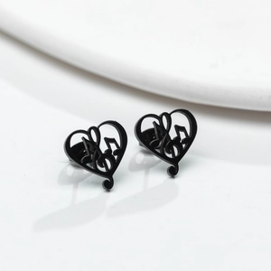 Macro detail of matte black musical note heart earrings on a minimalist white background