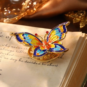 Vintage enamel butterfly brooch with colorful wings on open book in retro lighting