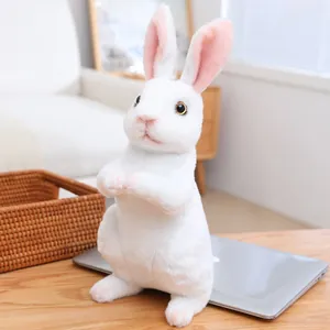 Close-up of white plush rabbit doll with soft long fur and pink inner ears on a wooden desk
